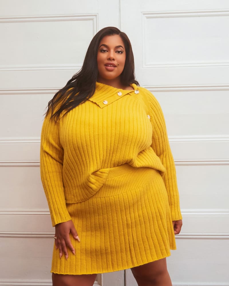 Side of a model wearing a size 4X Posey Knit Mini A Line Skirt in Mustard by Rebdolls. | dia_product_style_image_id:321243